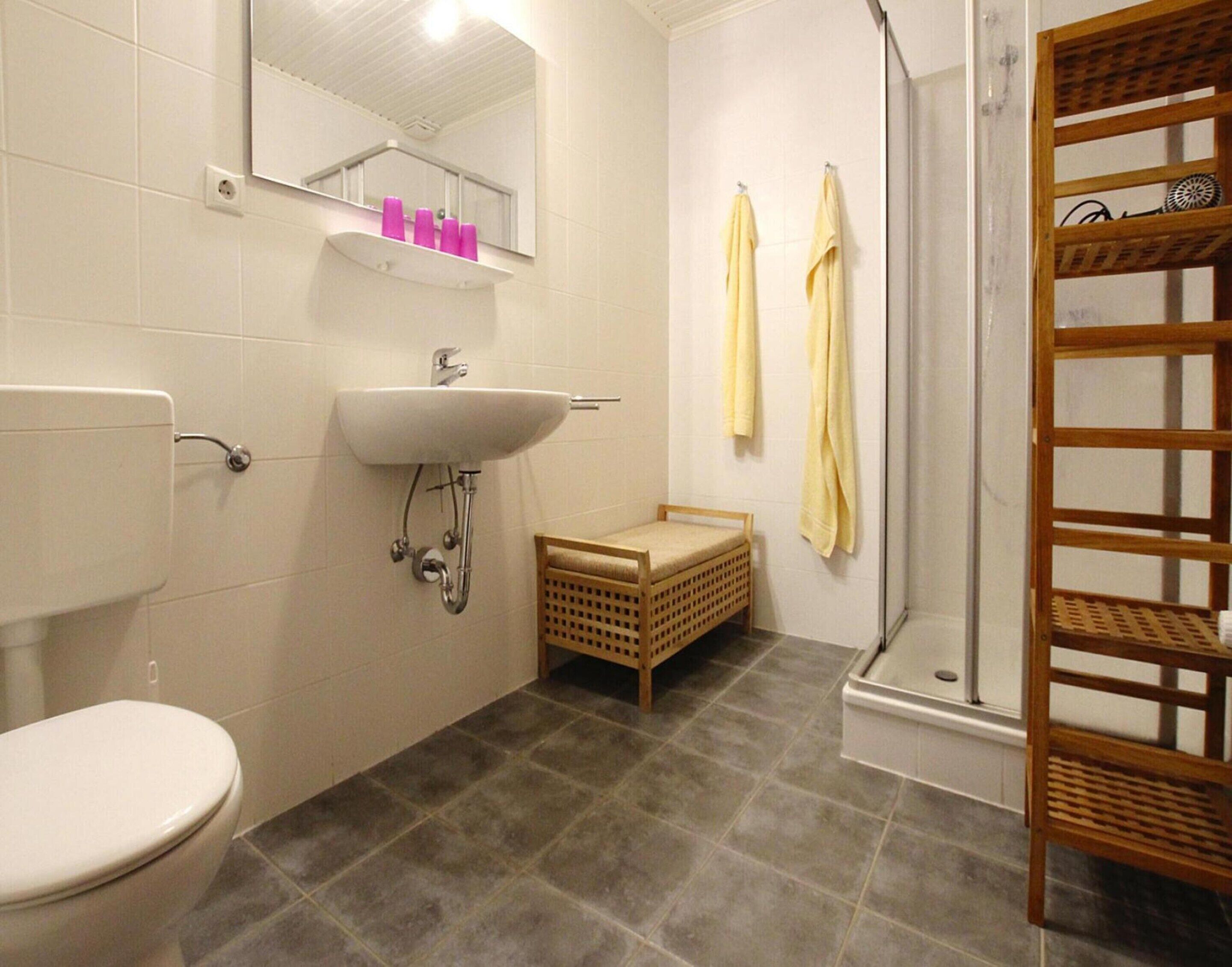 Une salle de bain équipée de toilettes, d’un lavabo, d’un miroir et d’une douche.
