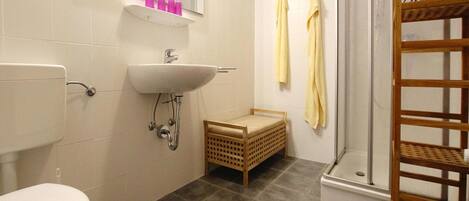 Une salle de bain équipée de toilettes, d’un lavabo, d’un miroir et d’une douche.