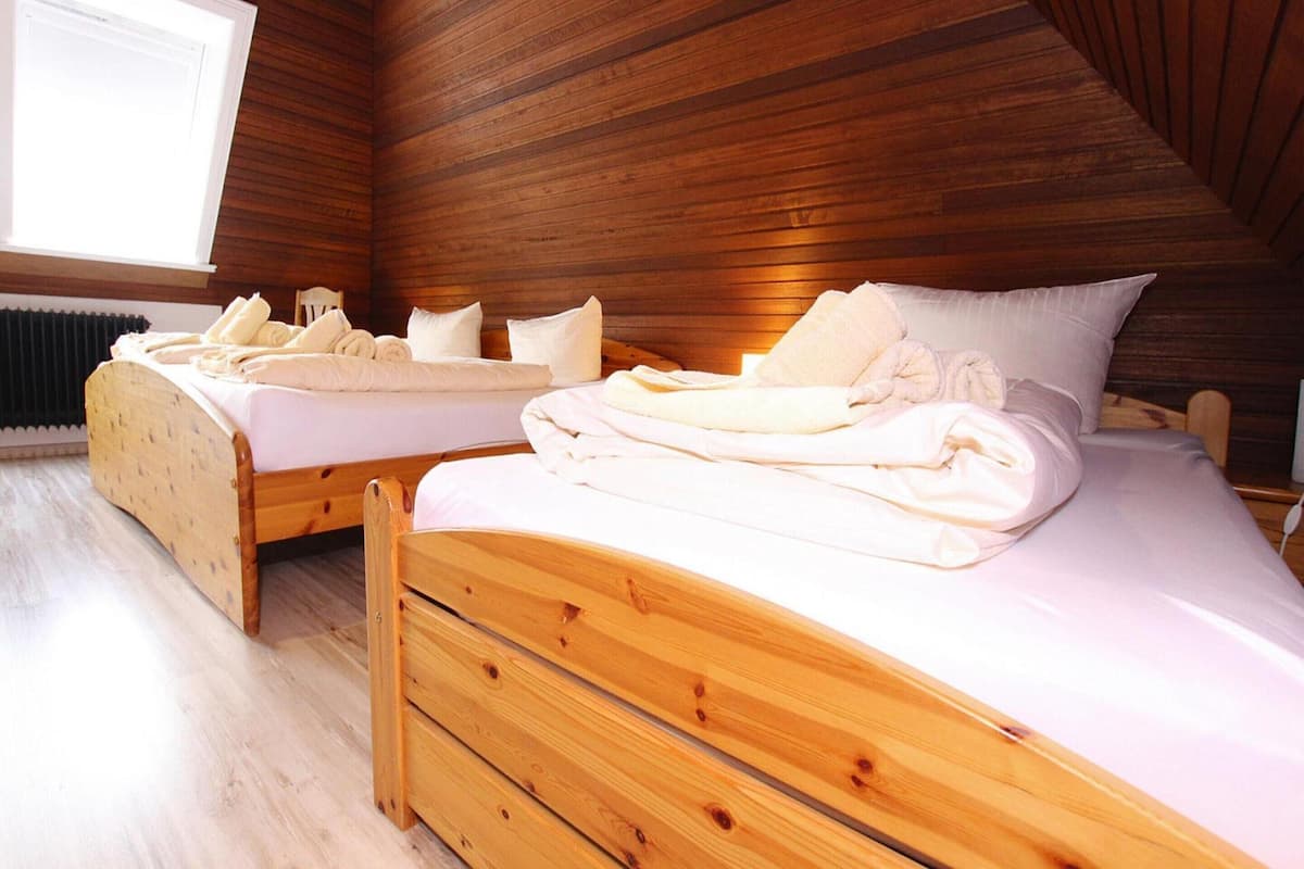 A room with two wooden beds, a window, and a radiator.
