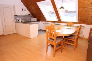 A kitchen with a dining area, wooden ceiling, and skylights. - Apartment in Westerland (Sylt)
