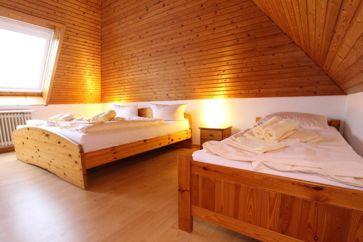 A room with two wooden beds, a window, and a radiator.
