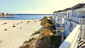 A beachfront hotel with multiple balconies, a sandy beach, and a pier in the background. - Semi-detached House, Ostseeresort Olpenitz (Kappeln)
