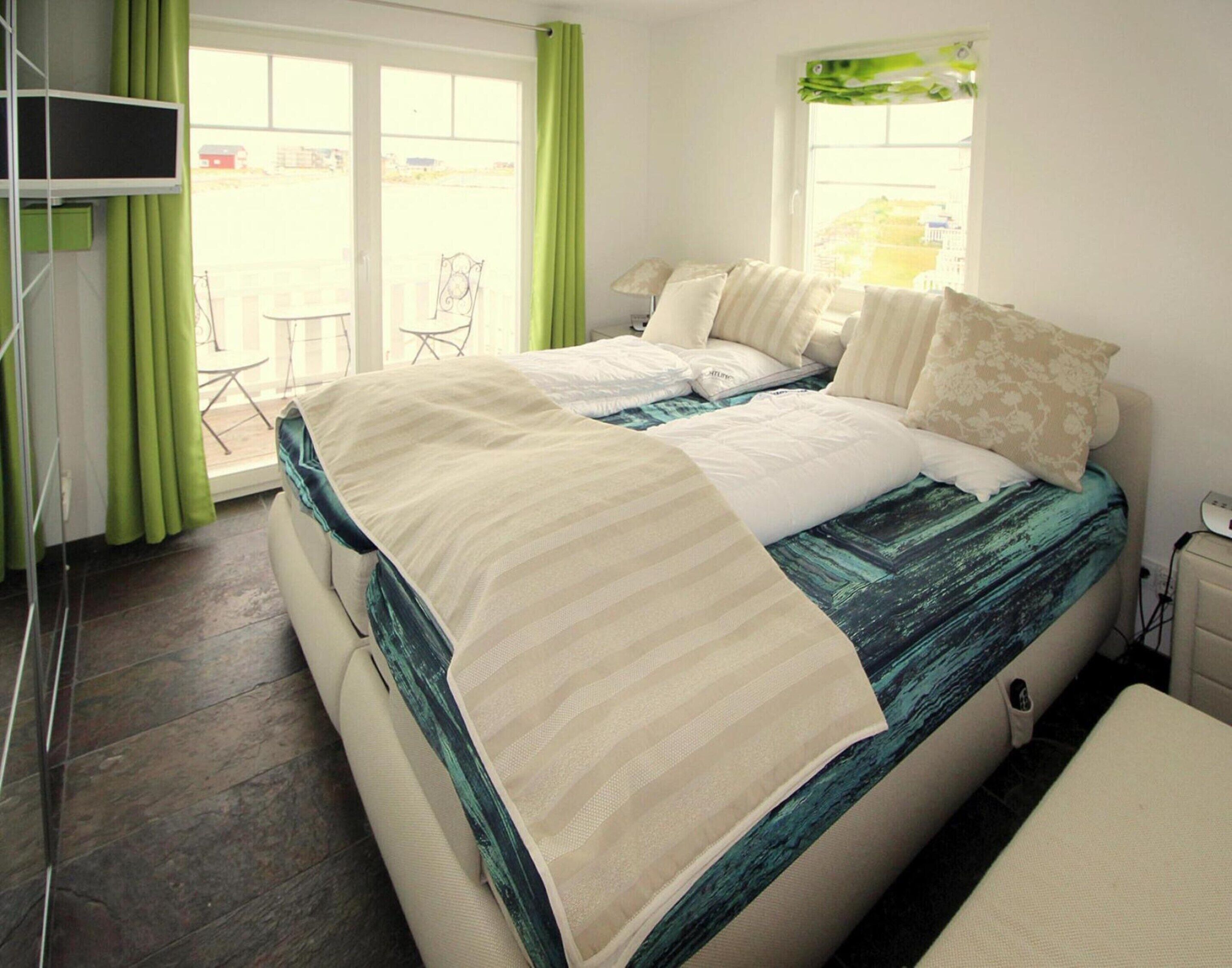 A bedroom with a bed, green curtains, a window, and a chair.
