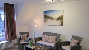 A living room with a sofa set, a coffee table, and a floor lamp. - Apartment in Westerland (Sylt)