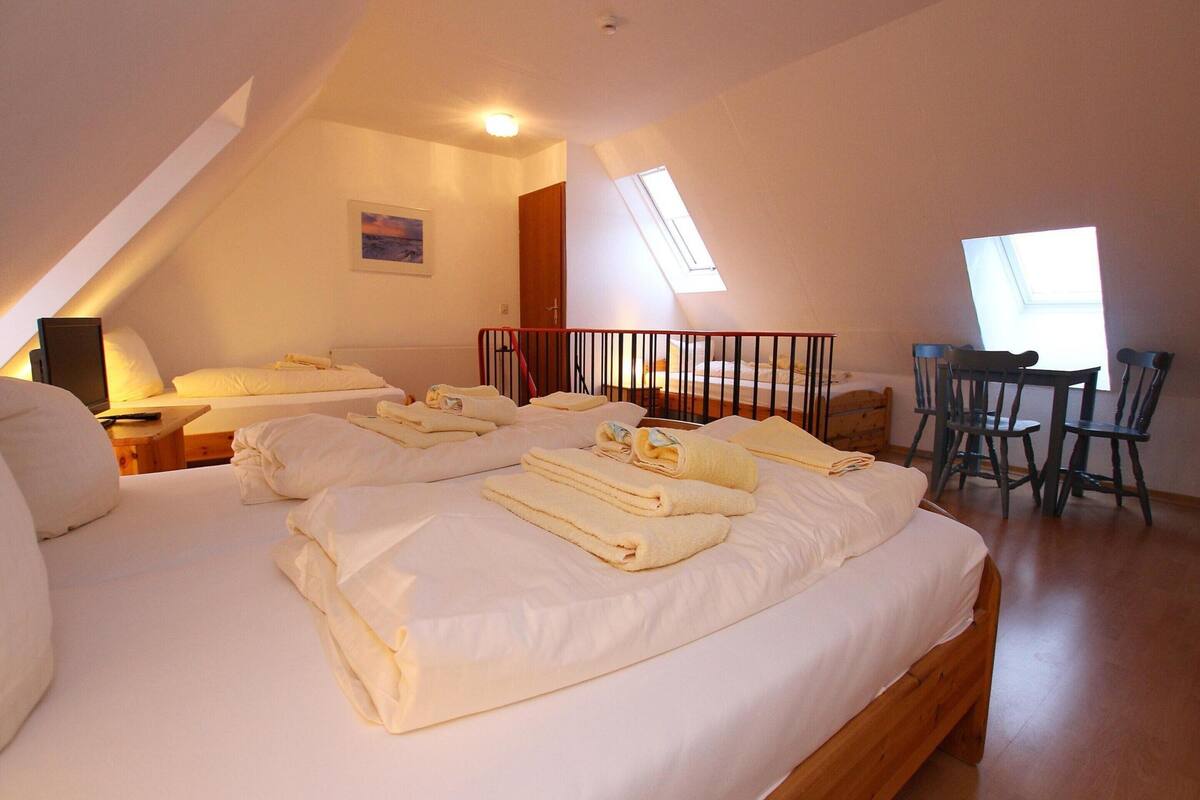 A bedroom with two beds, a desk, and a chair.