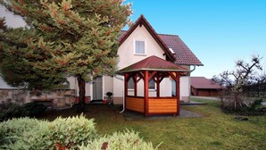 A house with a wooden gazebo, a stone foundation, and a red-tiled roof. - Apartments Spreewaldperle, Alt Zauche (Alt Zauche-Wußwerk)