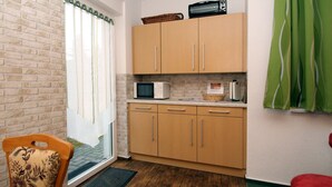 A compact kitchen with wooden cabinets, a microwave, and a toaster. - Apartments Spreewaldperle, Alt Zauche (Alt Zauche-Wußwerk)