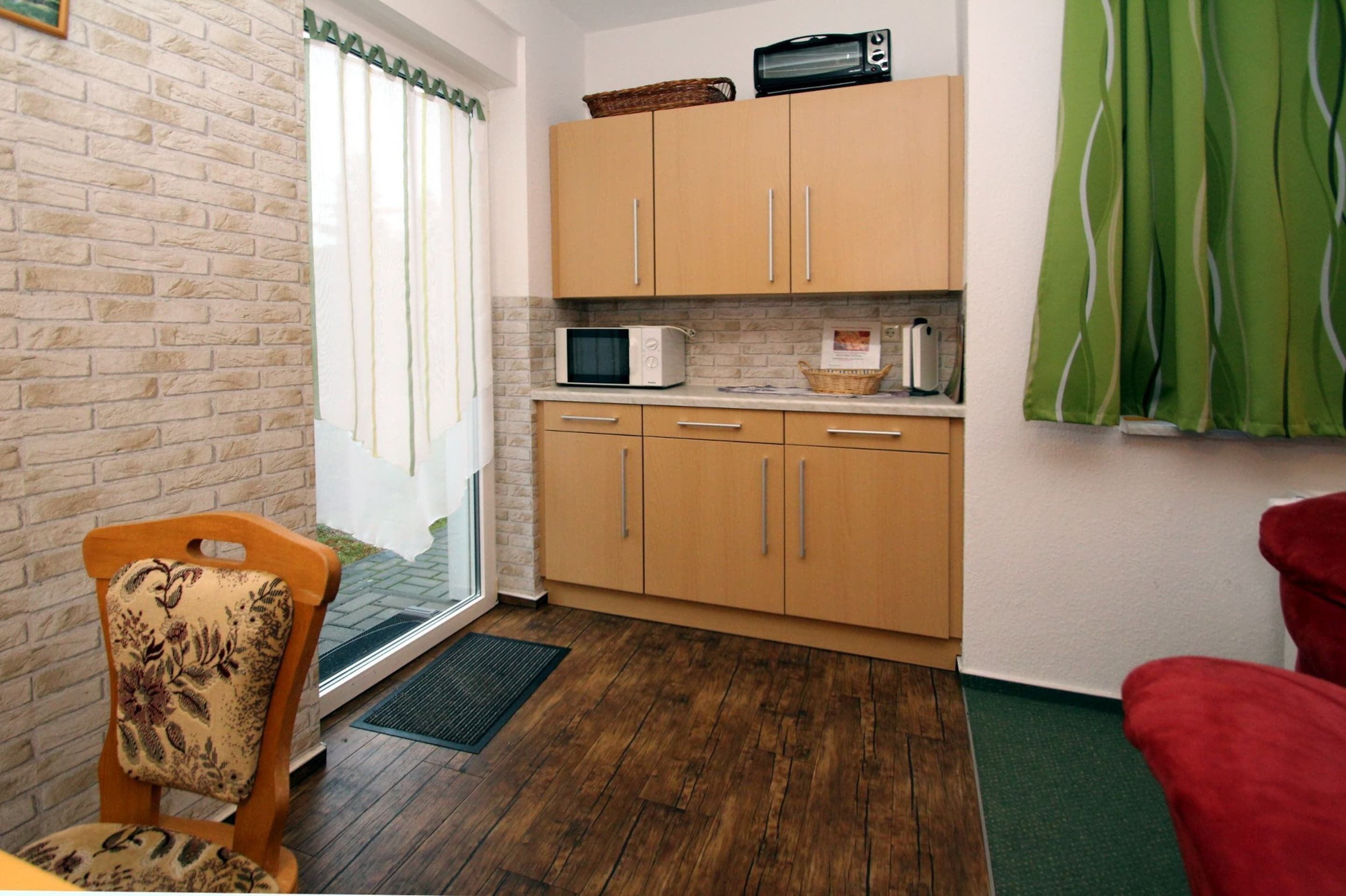 A compact kitchen with wooden cabinets, a microwave, and a small window.