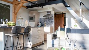 A modern kitchen with a dining area, featuring a bar, seating, and a chalkboard with writing. - Modern & Garden-view Holiday Home in Alphen (Alphen)