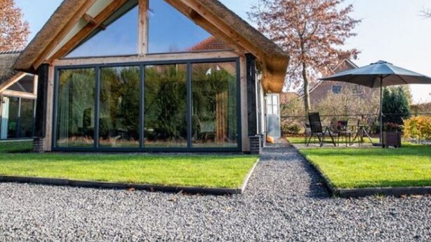 A modern house with a large glass window and a wooden roof. - Modern & Garden-view Holiday Home in Alphen (Alphen)