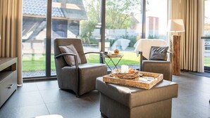 A spacious room with large windows, a sofa, a chair, and a small table with a tray. - Modern & Garden-view Holiday Home in Alphen (Alphen)