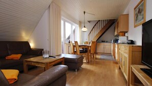 A modern living room with a brown leather sofa, a wooden coffee table, and a television on a wooden stand. - Apartment House Katharina, Westerland (Sylt)