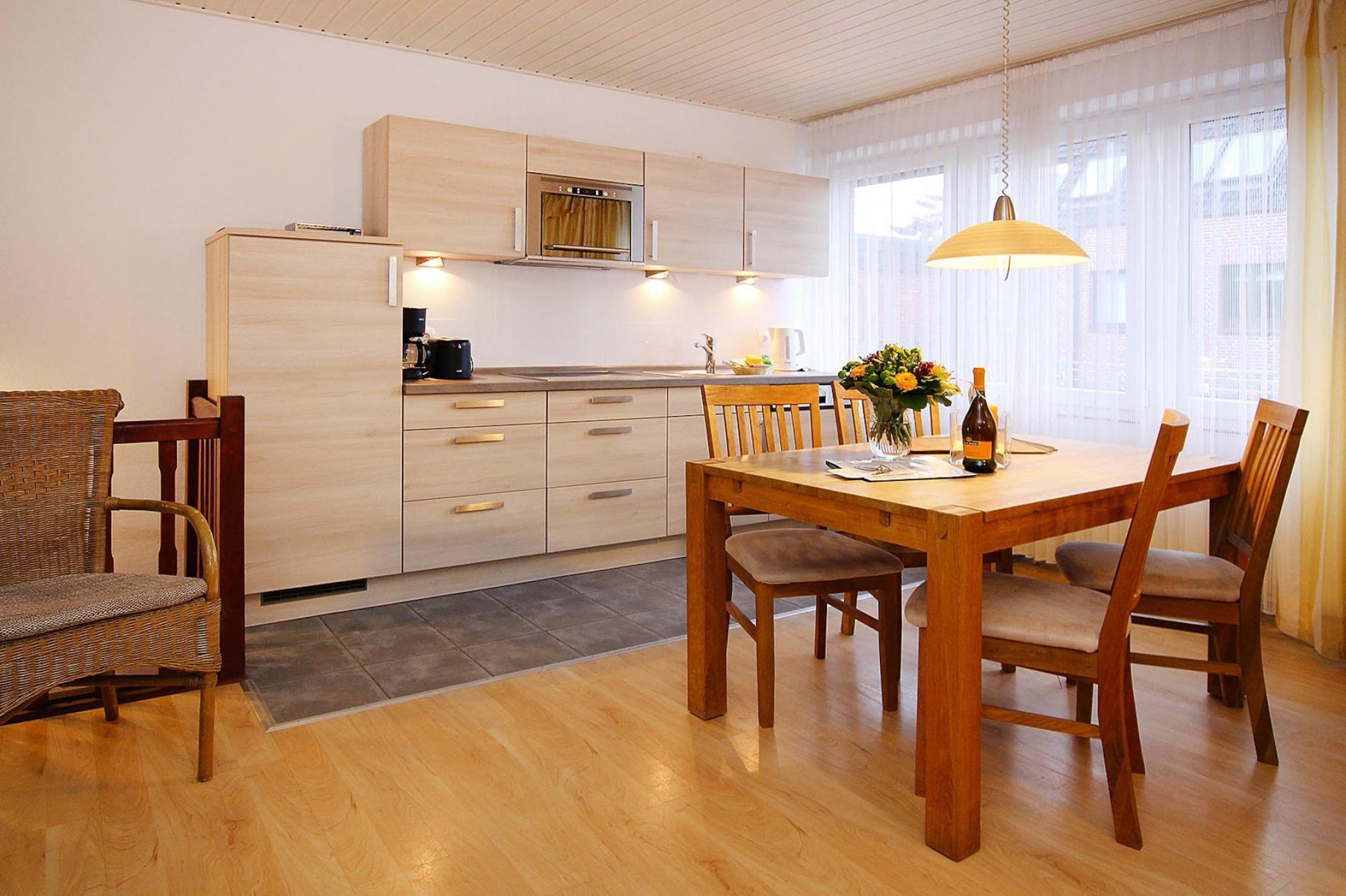 Et moderne køkken med træskabe, indbygget ovn samt spiseområde med et træbord og stole.