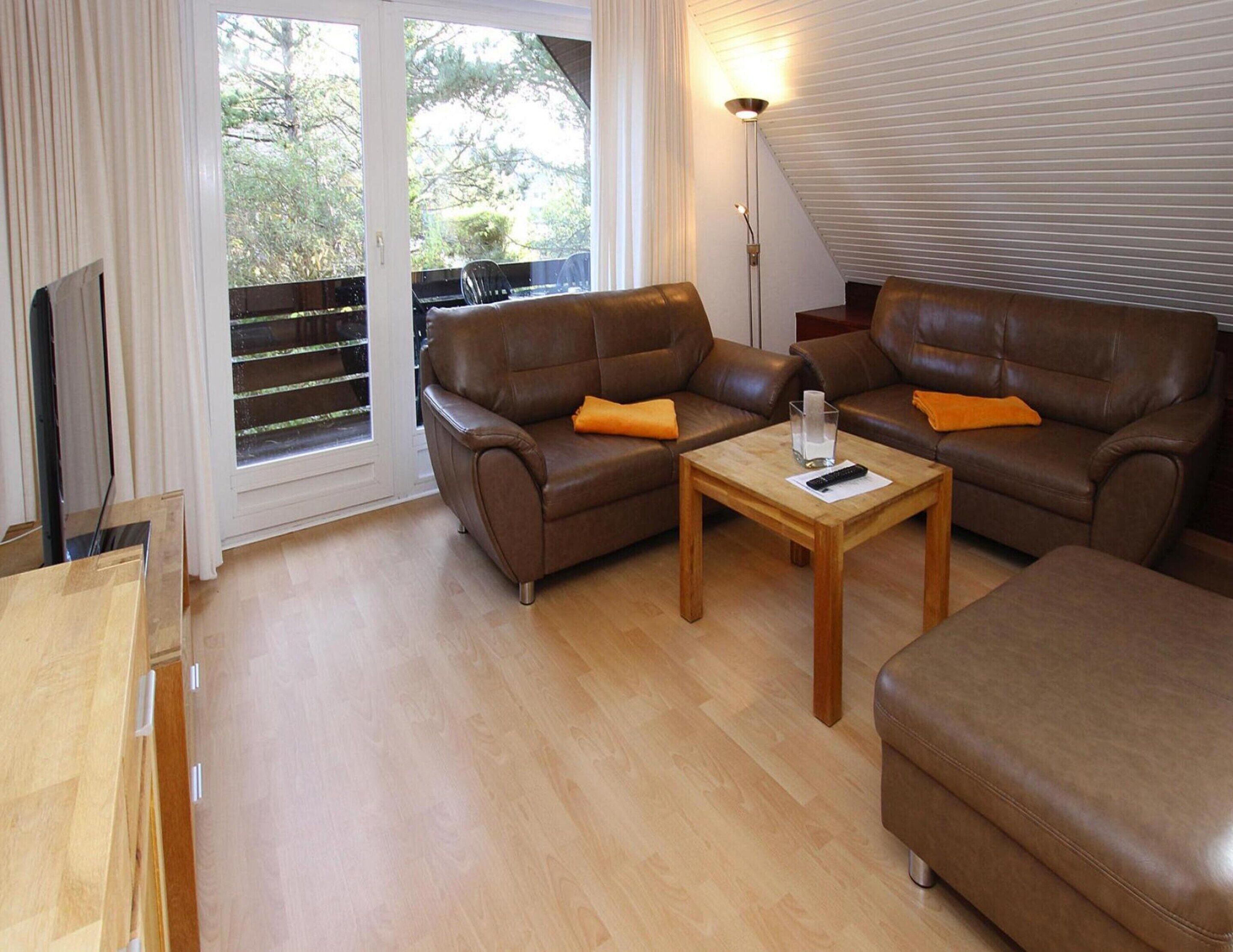 A living room with two brown leather sofas, a wooden coffee table, and a TV on a stand.