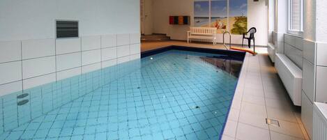 Una piscina con paredes de azulejos y un banco al fondo.