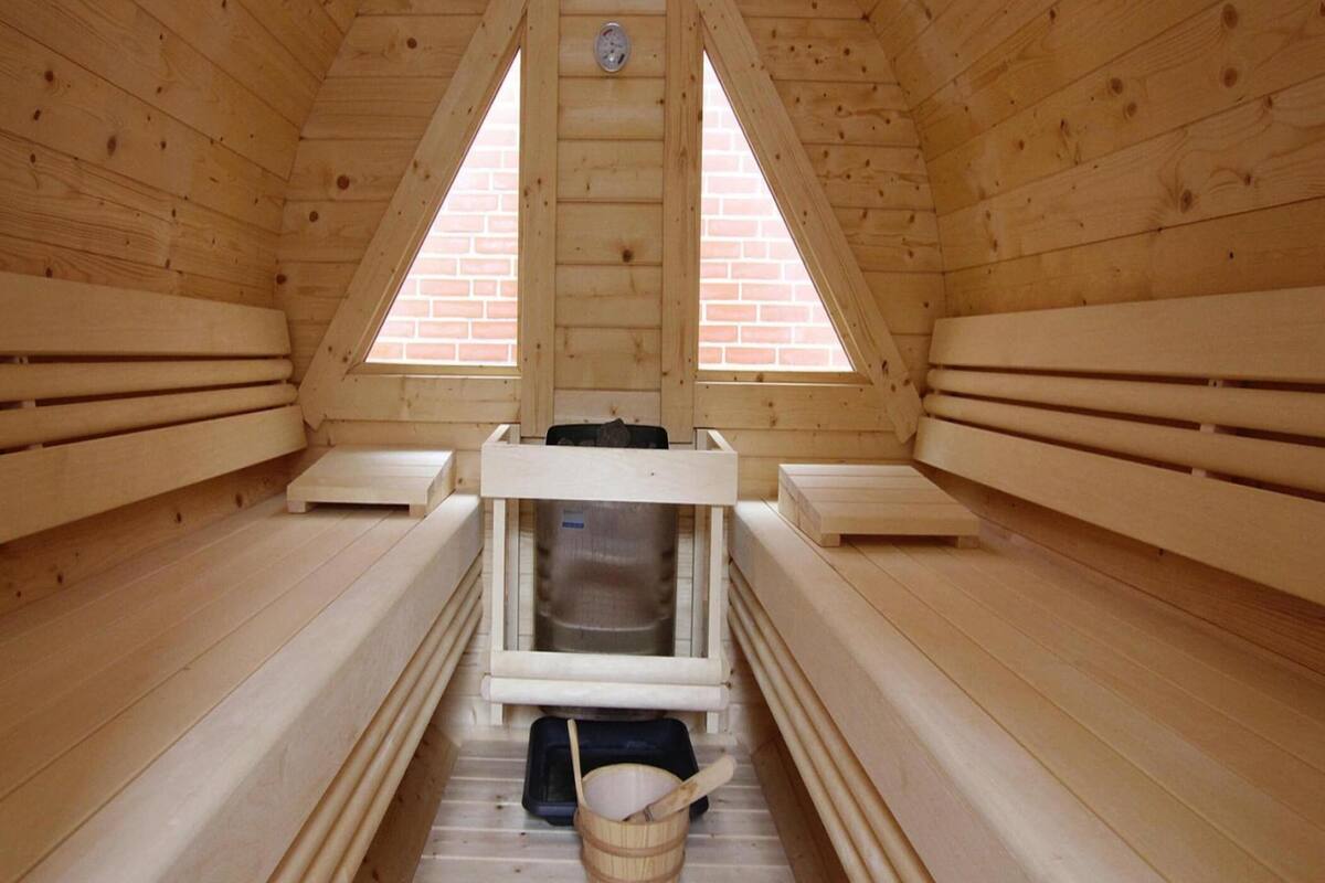 A sauna with wooden benches, a bench heater, and a bucket.
