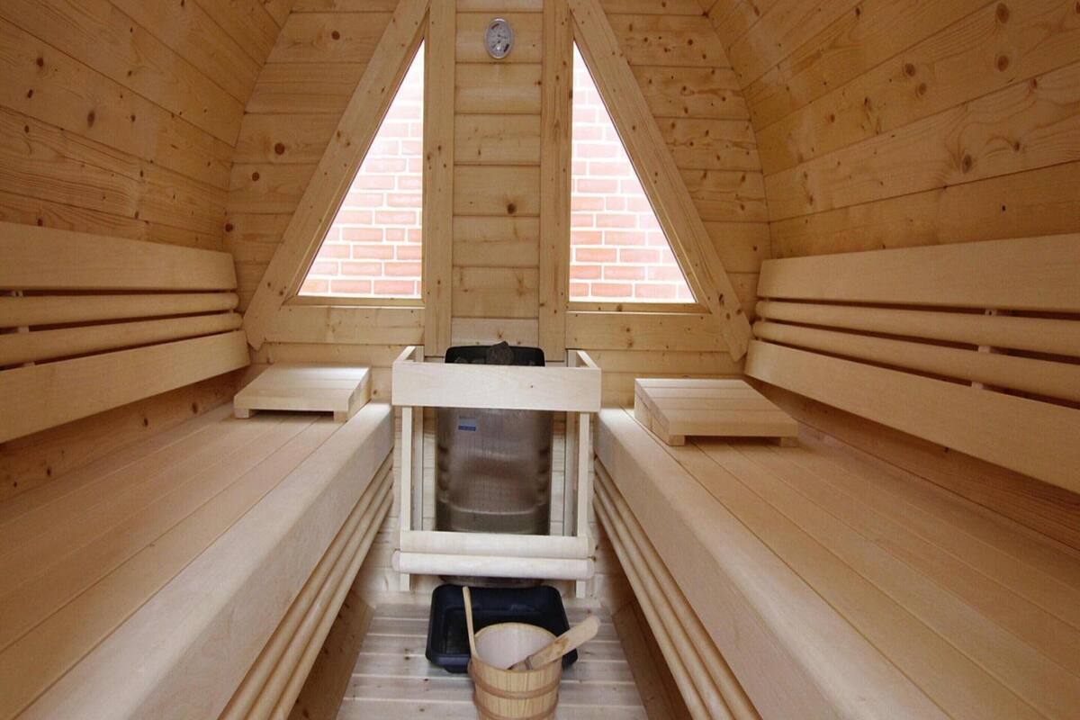 A sauna with wooden benches, a bench heater, and a bucket.