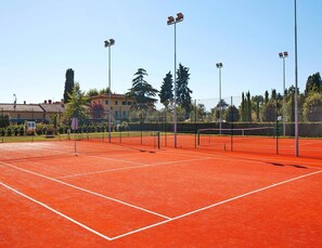 A tennis court with a net, surrounded by a fence, and outdoor lighting. - Hesse Farm Holiday Borgo Pinete (Fucecchio)
