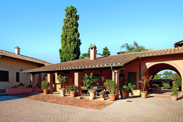 A courtyard with a covered seating area, potted plants, and a tall tree. - Hesse Farm Holiday Borgo Pinete (Fucecchio)