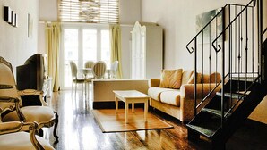 Un salon spacieux doté d’un plancher en bois, d’un canapé, d’une table basse et d’un escalier avec une rampe noire.