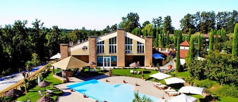 A modern hotel with a swimming pool, outdoor seating, and a well-maintained garden.