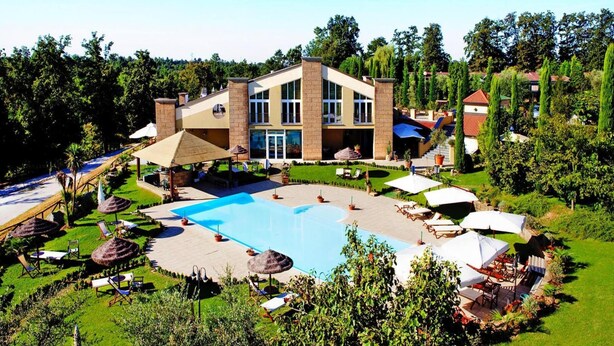 Un hôtel moderne doté d’une grande piscine, d’un espace extérieur aménagé et d’un jardin luxuriant.
