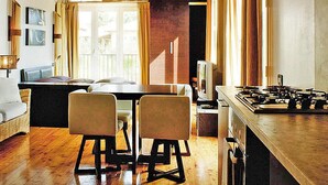 Un salon confortable avec un canapé, deux fauteuils, un téléviseur et un coin cuisine équipé d’une cuisinière.