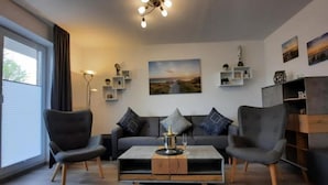 A modern living room with a sofa, two armchairs, a coffee table, and a painting on the wall. - Seepark Burhave, Burhave (Butjadingen)