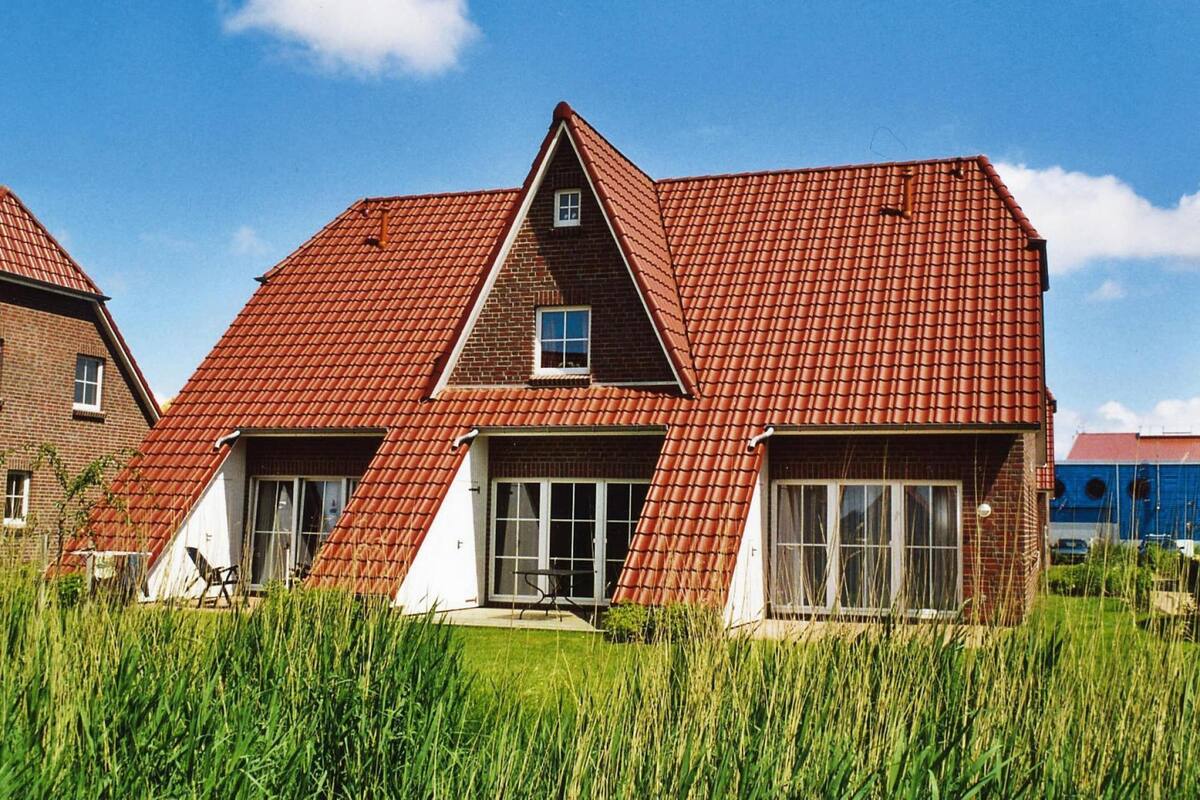 A house with a red-tiled roof, a central chimney, and a small window.