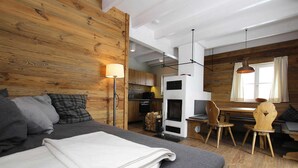 A cozy room with a bed, a small table, and a chair. There's a wooden wall and a window with curtains. - Ferienhauser im Schierke Harzresort (Wernigerode)