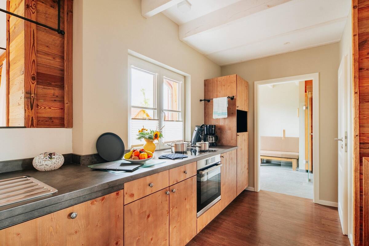 A modern kitchen with wooden cabinets, a large window, and a built-in oven.
