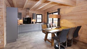 A modern kitchen with grey cabinets, a black refrigerator, and a dining area with a wooden table and four chairs. - Cottage, Schierke (Wernigerode)