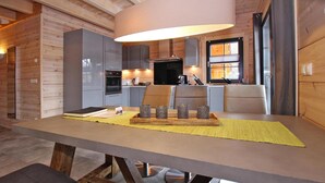 A modern kitchen with grey cabinets, a central island with stools, and a dining table with a yellow placemat. - Cottage, Schierke (Wernigerode)
