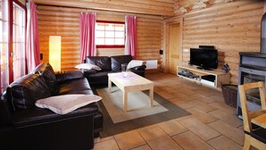 A log cabin interior with a leather sofa, a wooden coffee table, a television on a stand, and a fireplace. - Blockhaus, Schierke (Wernigerode)