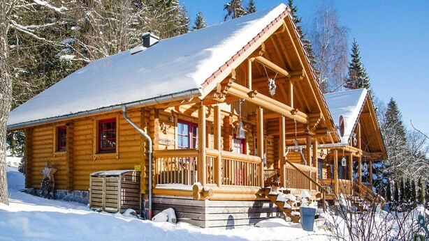 A log cabin with a snow-covered roof, wooden porch, and a chimney. - Blockhaus, Schierke (Wernigerode)
