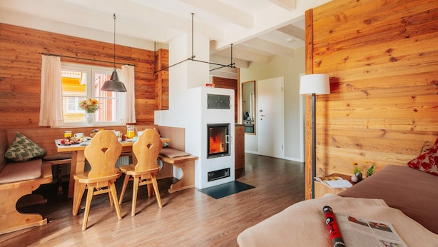 A cozy room with a wooden interior, a dining area with wooden chairs, a table with breakfast items, and a fireplace. - Holiday Homes in the Schierke Harzresort on the Brocken, Schierke (Wernigerode)