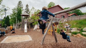 Une aire de jeux avec des structures en bois et une maison de jeux couverte.