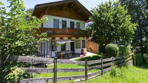 A two-story chalet with a balcony, a covered patio, and a wooden fence. - Holiday Home Emberger, Fugen (Fuegenberg)