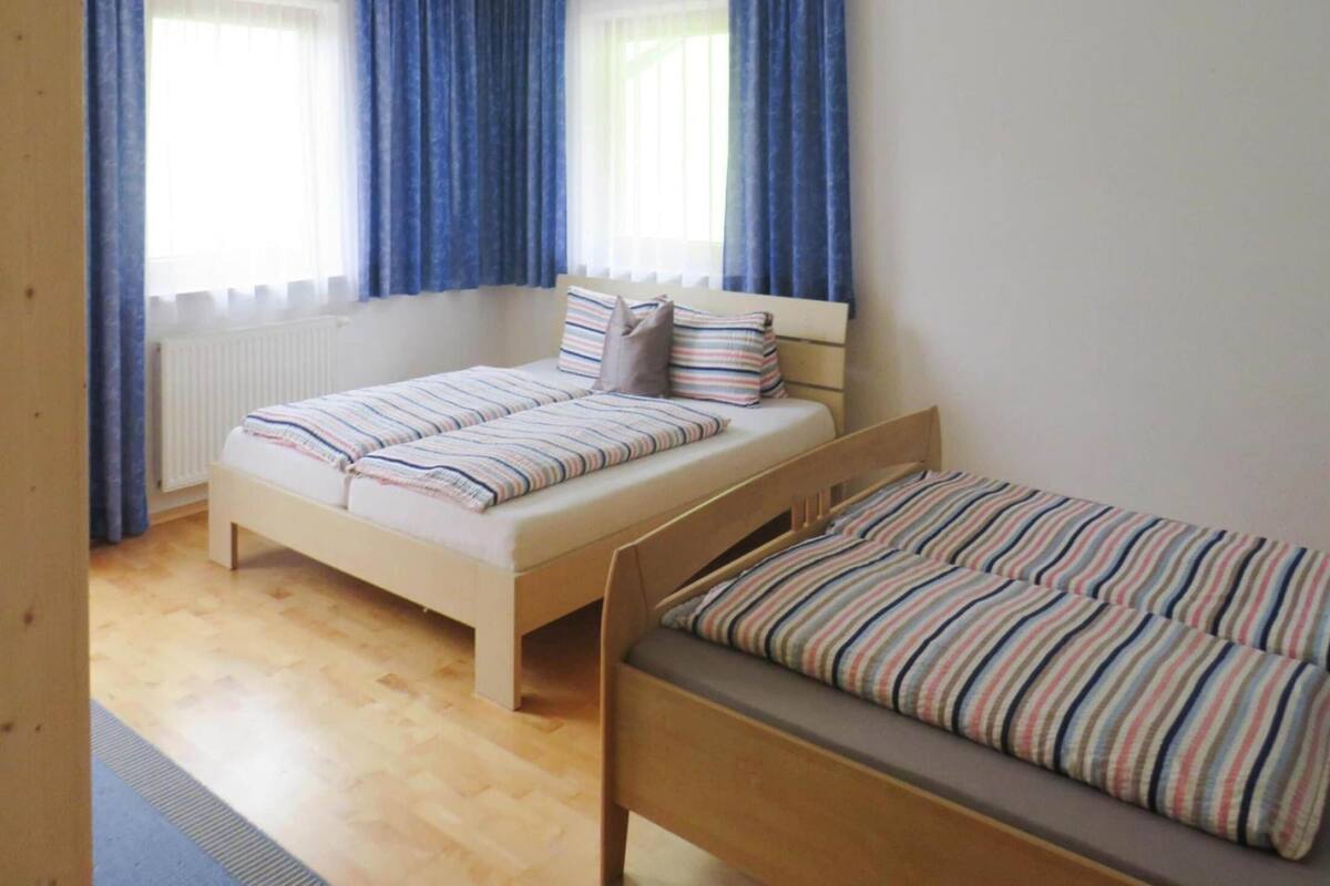 Une chambre à coucher avec un grand lit, un petit lit et une fenêtre avec des rideaux.