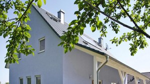 Un edificio moderno a due piani con tetto piatto, ampie finestre e un portico coperto.