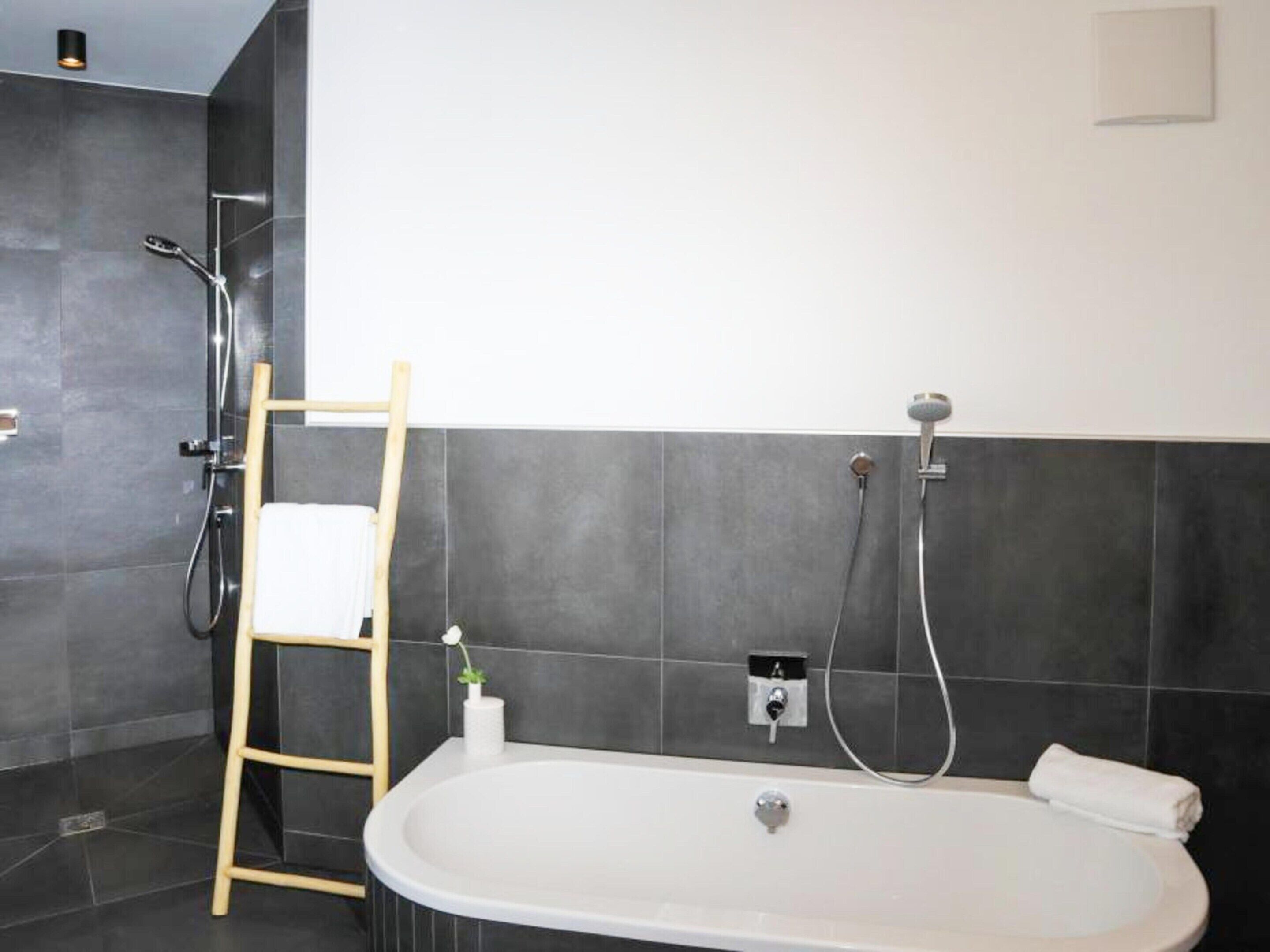 A modern bathroom with a freestanding bathtub, a showerhead, and a towel rack.