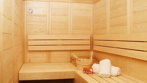 Una sauna de madera con bancos, un cubo, toallas y un termómetro.