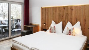 Una habitación de hotel moderna con una cama grande, cabecera de madera y una puerta corredera de cristal a un balcón.