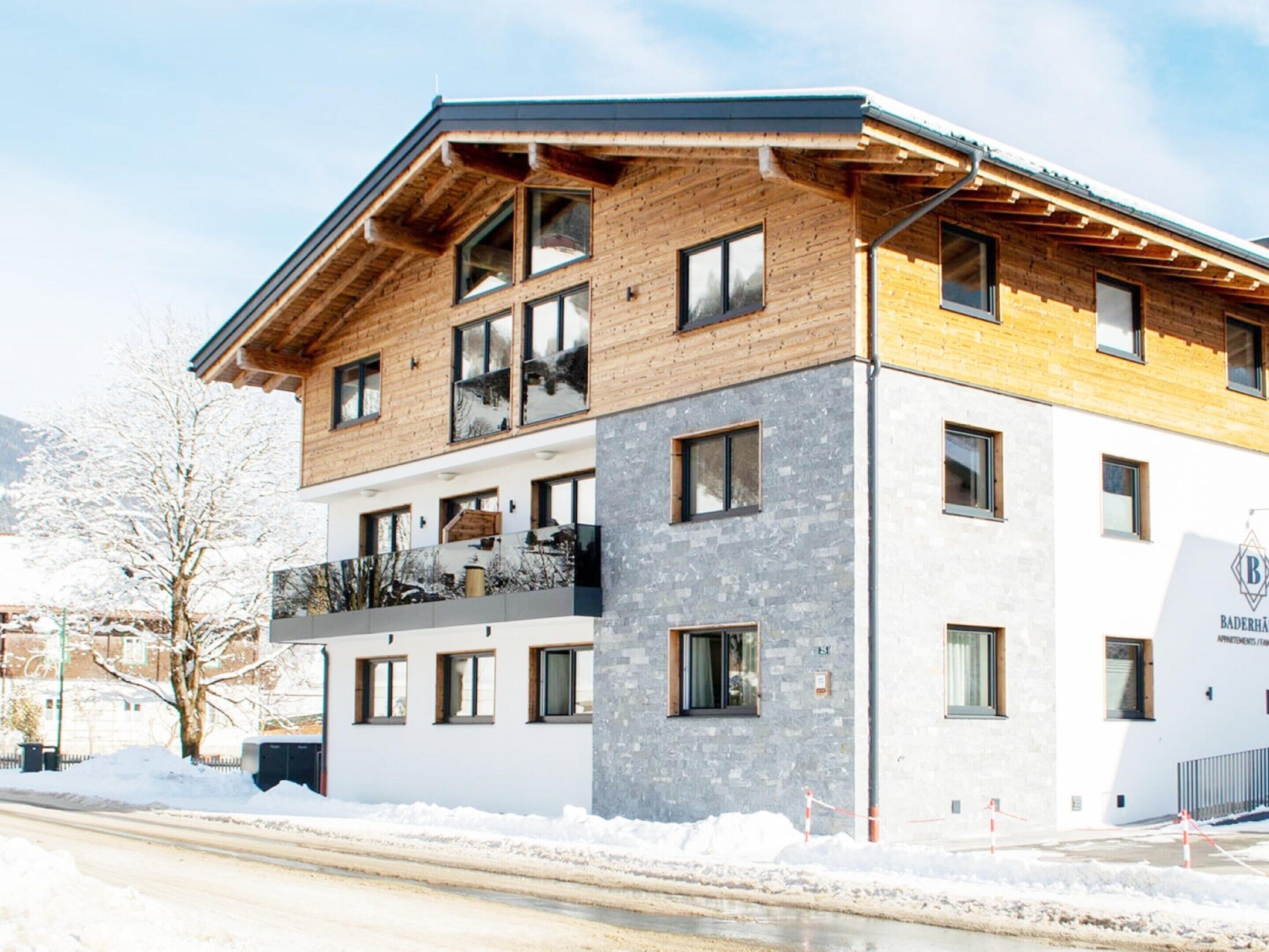 A multi-story building with a wooden facade, large windows, and a balcony.