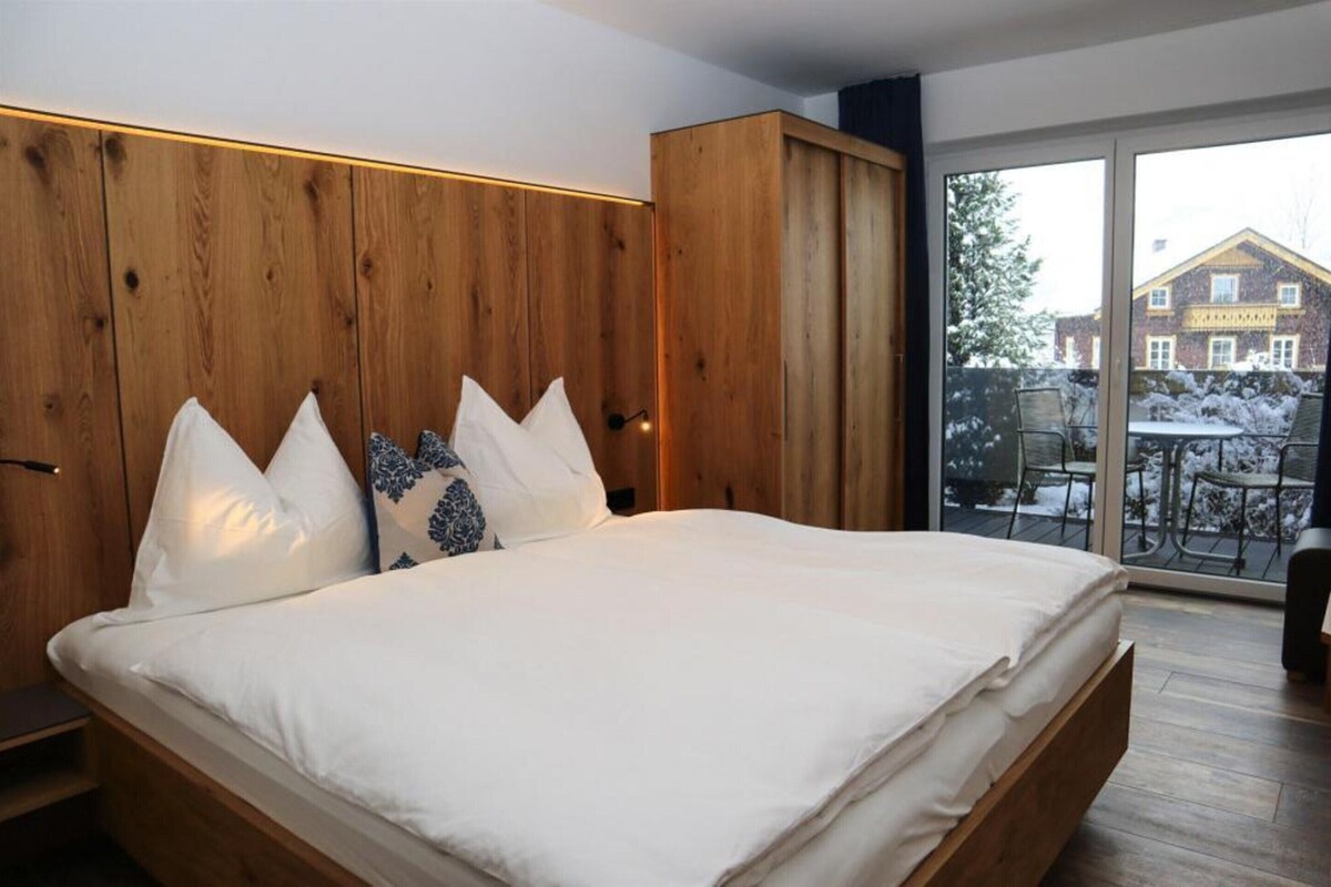 Ein Schlafzimmer mit einem großen Bett, einem Holzschrank und Blick auf eine verschneite Landschaft.