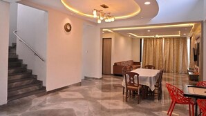 Ein modernes Interieur mit einer Treppe, einem Essbereich mit Tisch und Stühlen sowie einem Wohnbereich mit Sofa und Vorhängen.