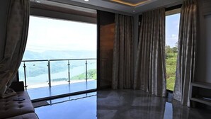 Ein geräumiges Zimmer mit großem Fenster und Blick auf See und Berge.