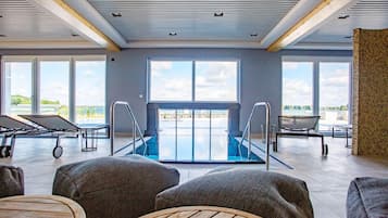 Amplio espacio interior con piscina, asientos y grandes ventanales que ofrecen vistas al exterior.