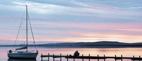 A calm lake with a sailboat docked at a pier.