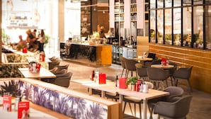 A modern cafe with wooden tables and chairs, a bar area, and large windows offering a view of the city. - Apartments in the Maremuritz Yachthafen Resort, Waren an der Muritz (Waren (Müritz))
